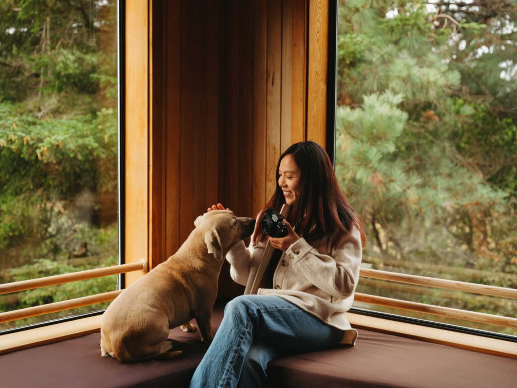 Fotografin streichelt ihren Hund und hält die X-T30 iii in einer Hand