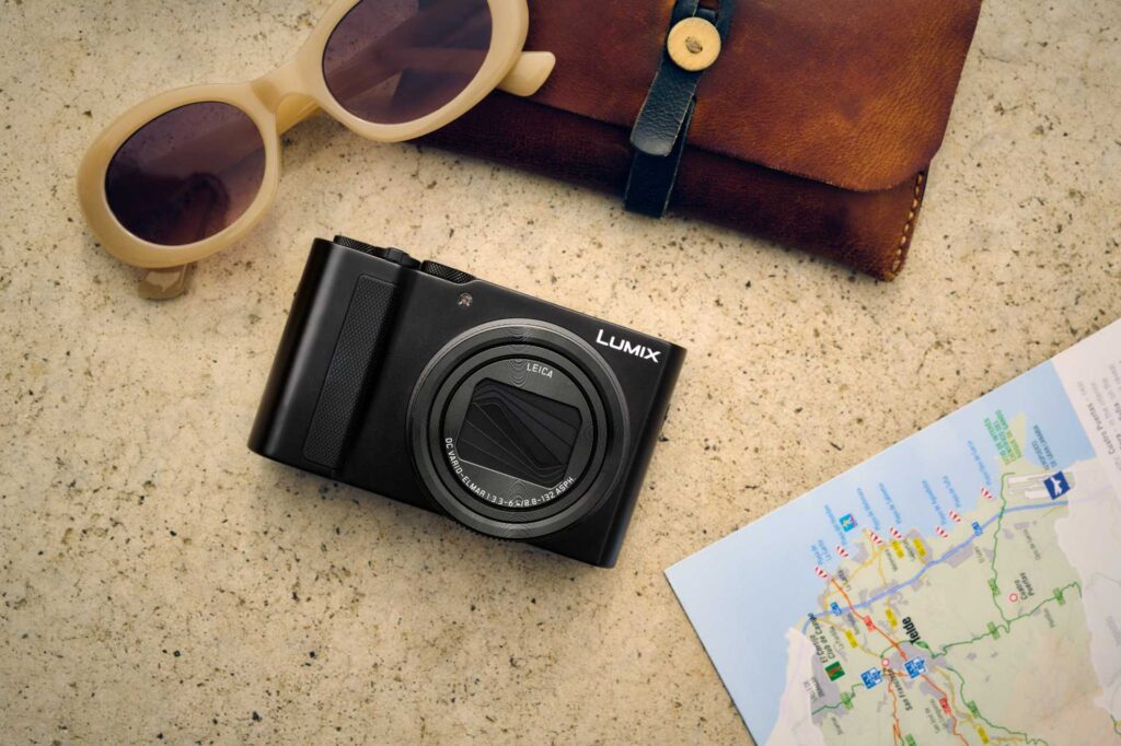 Lumix DC TZ-300 auf dem Tisch mit Sonnenbrille und Karte.