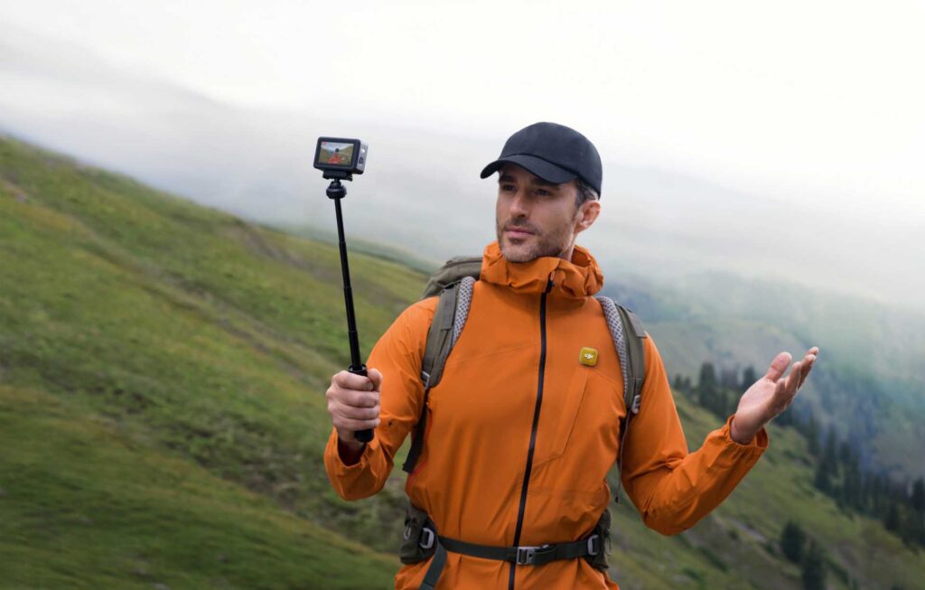 Man in Wanderkleidung nutzt eine DJI Actioncam in Verbindung mit dem DJI Mic Mini 2 zur Moderation.