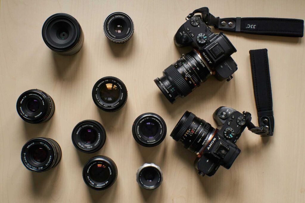 Eine DSLR und eine DSLM Kamera auf dem Tisch neben verschiedenen Objektiven.
