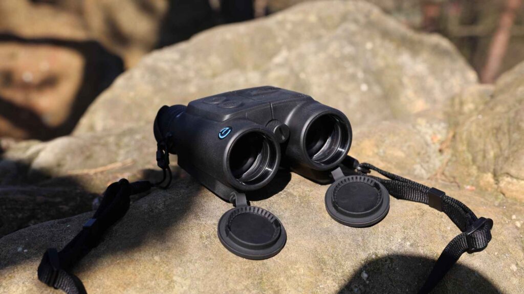 Frontansicht des Steiner eDiscovery 10x42 Fernglases auf Felsen, Objektivschutzkappen geöffnet und danebenliegend.