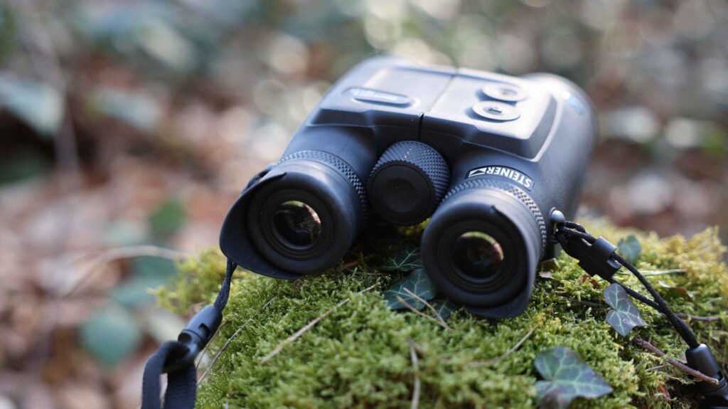 Steiner eDiscovery 10x42 Fernglas auf moosigem Untergrund im Wald, Frontansicht mit Fokus auf die Augenmuscheln.
