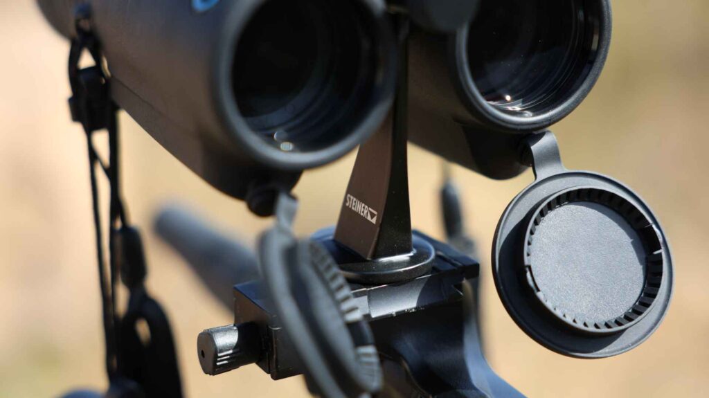 Detailaufnahme der Stativhalterung des Steiner eDiscovery 10x42 Fernglases mit geöffnetem Objektivdeckel.